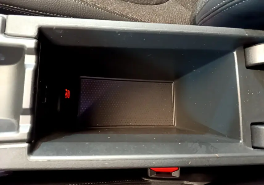 Gros plan sur le rangement central intérieur gris foncé de la BMW Série 1 Edition Sport avec témoin rouge allumé.