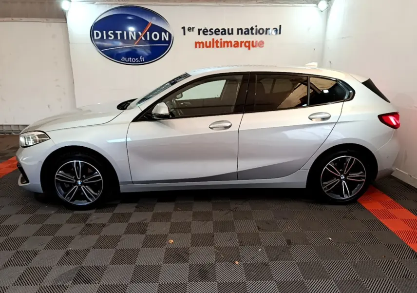 Profil côté gauche d'une BMW Série 1 gris clair 2021 Edition Sport, avec jantes alliage et feux arrière LED visibles.