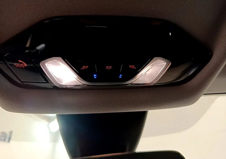 Plafonnier intérieur avec éclairage et bouton SOS de la BMW Série 1 gris clair, vue en contre-plongée depuis l'habitacle.