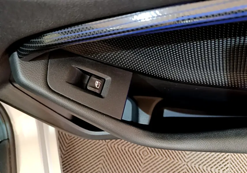 Gros plan sur le bouton de commande de la vitre côté conducteur dans une BMW Série 1 gris clair, intérieur noir.