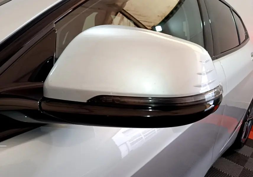 Gros plan sur le rétroviseur droit blanc avec clignotant intégré d'une BMW Série 1 gris clair Edition Sport 2021.