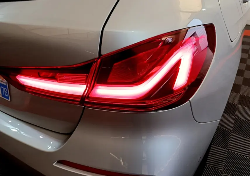 Gros plan sur le feu arrière droit allumé d'une BMW Série 1 gris clair, version Edition Sport 2021.
