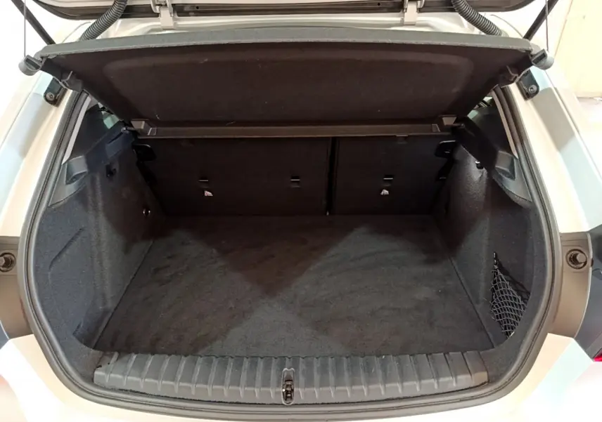 Coffre ouvert vu de l'arrière d'une BMW Série 1 gris clair, montrant l'espace de chargement vide et la tablette de séparation.