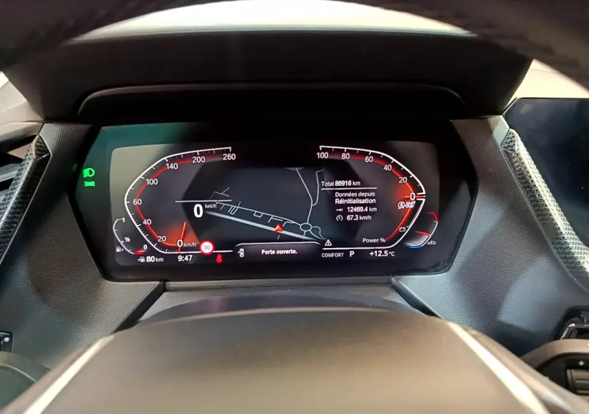 Vue rapprochée du tableau de bord numérique de la BMW Série 1 gris clair avec affichage multifonctions et indicateurs rouges.