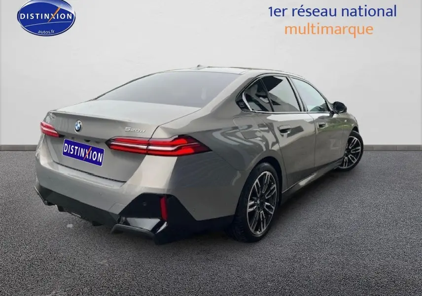 BMW Série 5 520da gris vue 3/4 arrière droit, jantes alliage et feux arrière LED distinctifs.