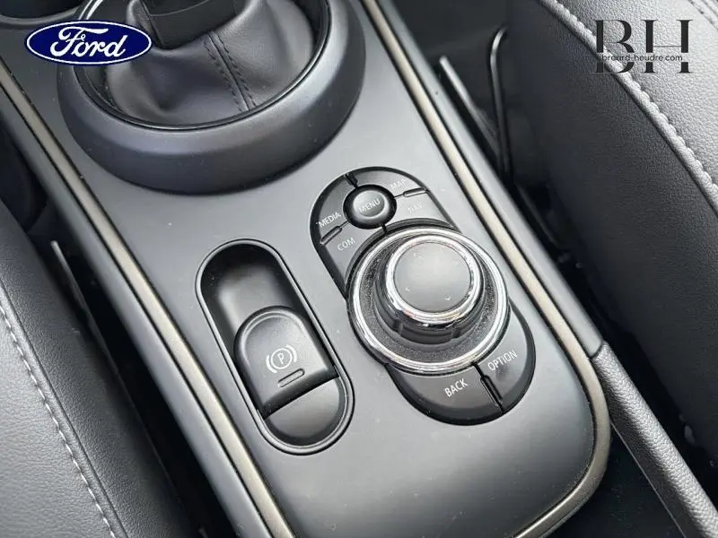 Gros plan sur la console centrale noire du MINI Countryman Melting Silver III avec molette de commande et frein électrique.