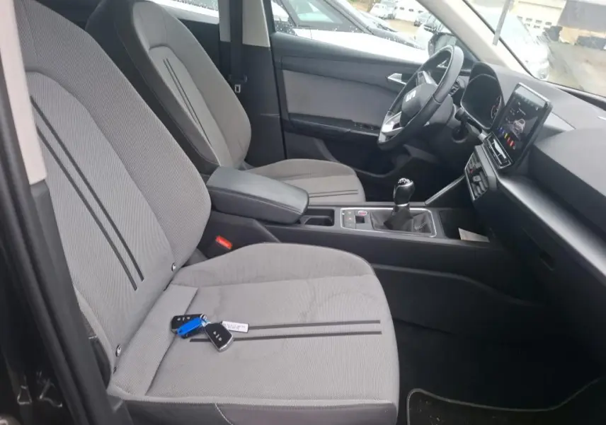 Vue intérieure côté conducteur du SEAT Leon 2.0 TDI 115 STYLE 2021, sièges tissu gris avec clés posées dessus.