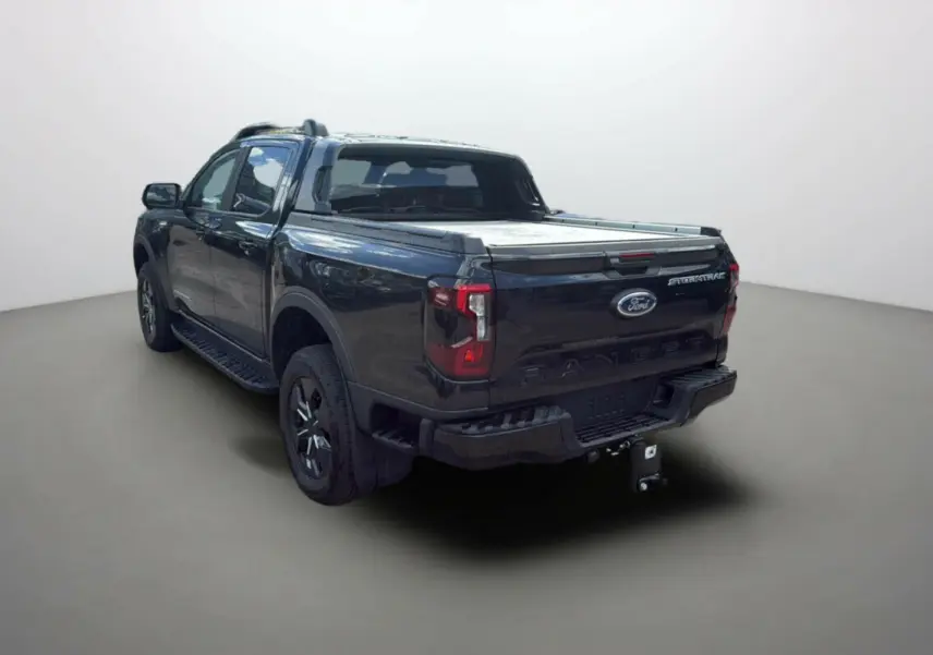 Ford Ranger 2.3 PHEV noir agate vu 3/4 arrière droit avec benne couverte et attelage visible.