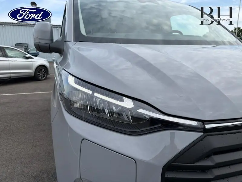 Gros plan sur le phare avant gauche du Ford Transit Custom Fourgon gris Matter Spéciale avec calandre noire.