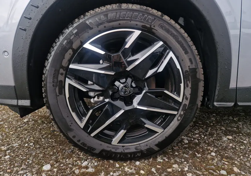 Gros plan sur la roue avant droite du Peugeot 3008 gris Artense, jante alliage noire et argentée au design géométrique.