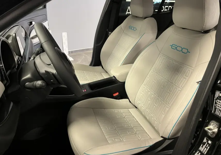 Intérieur vue côté gauche du FIAT 600 noir, sièges ivoire embossés avec logo 600 bleu azur et volant soft-touch.