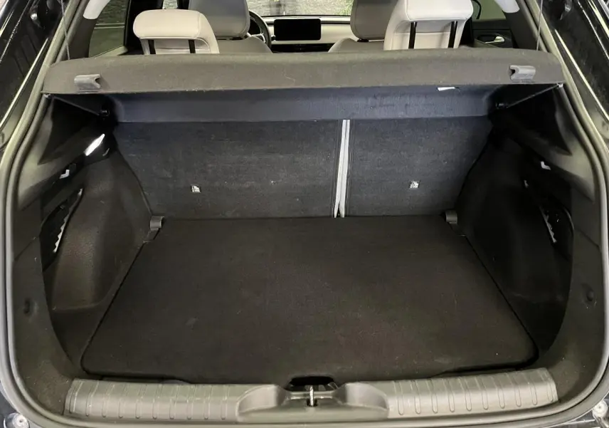 Coffre ouvert vu de l'arrière d'une FIAT 600 noire, montrant l'espace de chargement et la banquette arrière.