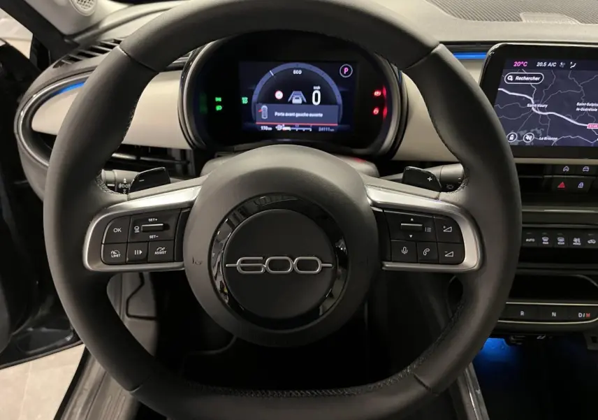Vue rapprochée du volant noir du Fiat 600 1.2 Hybrid 2024 avec commandes intégrées et tableau de bord numérique.