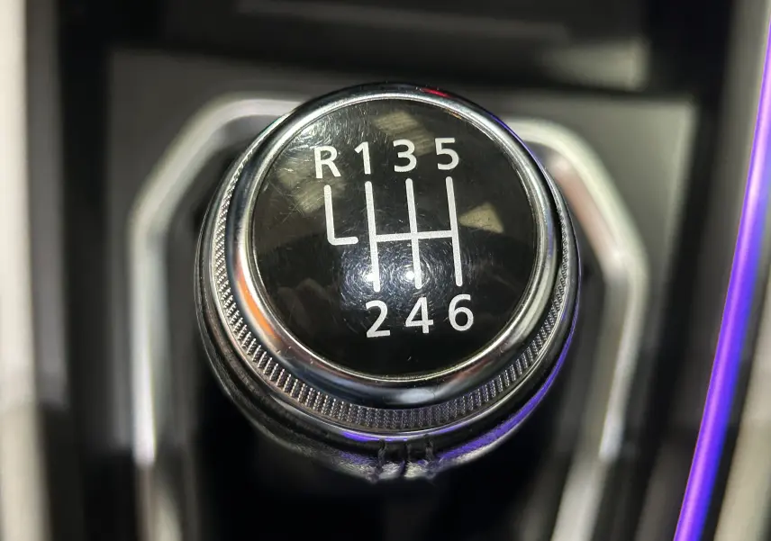 Gros plan sur le levier de vitesses manuel noir et chrome de la Renault Clio V TCe 90 TECHNO rouge, montrant les six rapports et la marche arrière.