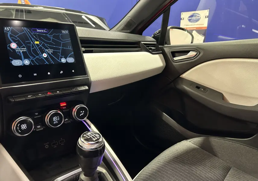 Intérieur de Renault Clio V TCe 90 TECHNO 2023, vue côté passager montrant la console centrale avec boîte manuelle et écran tactile.