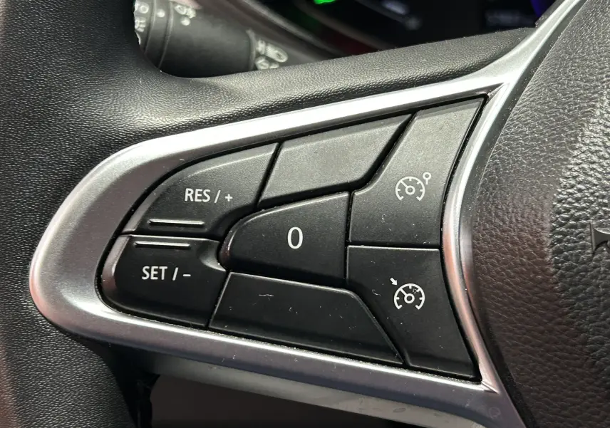 Gros plan sur les commandes de régulateur de vitesse au volant d'une Renault Clio V rouge TCe 90 TECHNO 2023