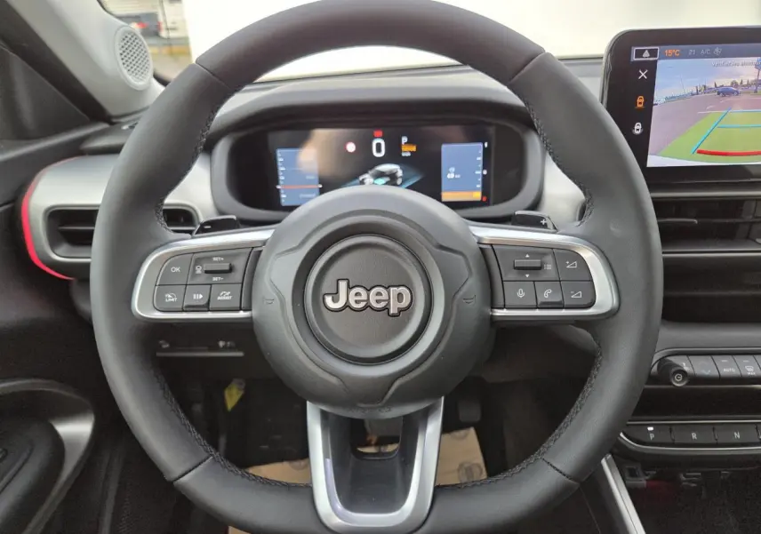 Volant Jeep noir avec commandes intégrées, tableau de bord numérique et écran tactile affichant la caméra de recul.