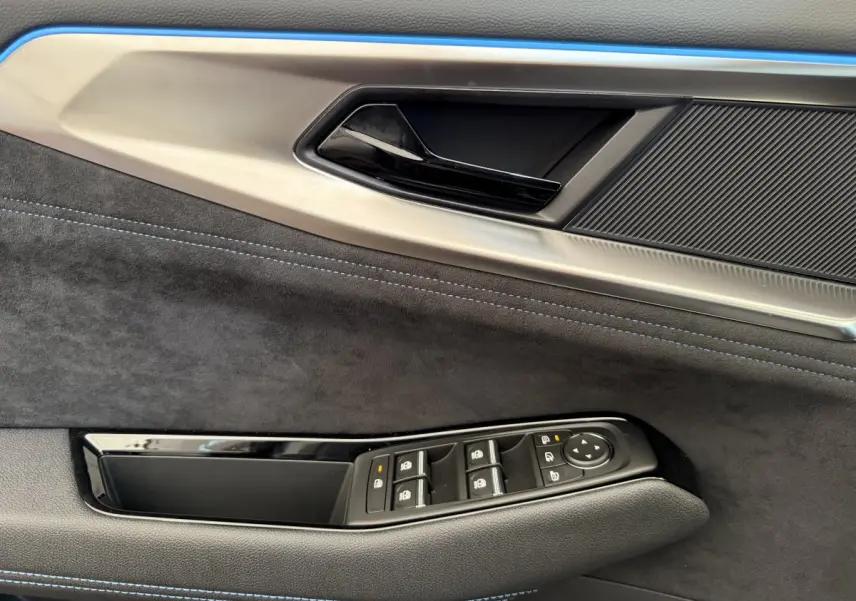 Gros plan sur la porte côté gauche du Renault Espace gris foncé esprit Alpine, avec commandes de vitres et surpiqûres bleues.