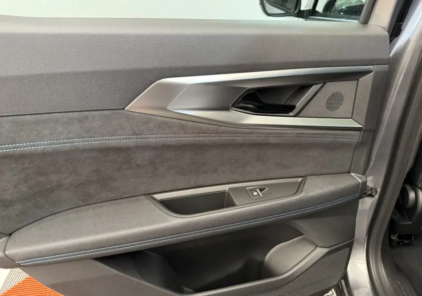 Gros plan sur la porte intérieure côté droit du Renault Espace gris foncé esprit Alpine 7PL avec surpiqûres bleues et poignée argentée.