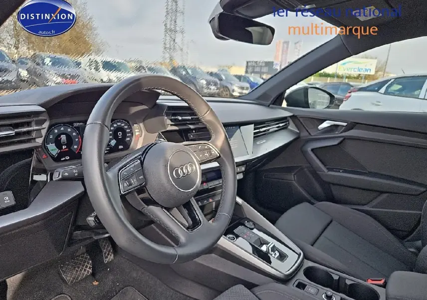 Vue intérieure côté conducteur de l'Audi A3 Sportback 45 TFSI e 2024 avec volant cuir multifonction et tableau de bord digital.