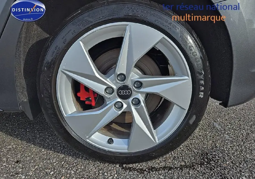 Gros plan sur la jante avant droite argentée d'une Audi A3 Sportback gris Daytona avec étrier de frein rouge visible.