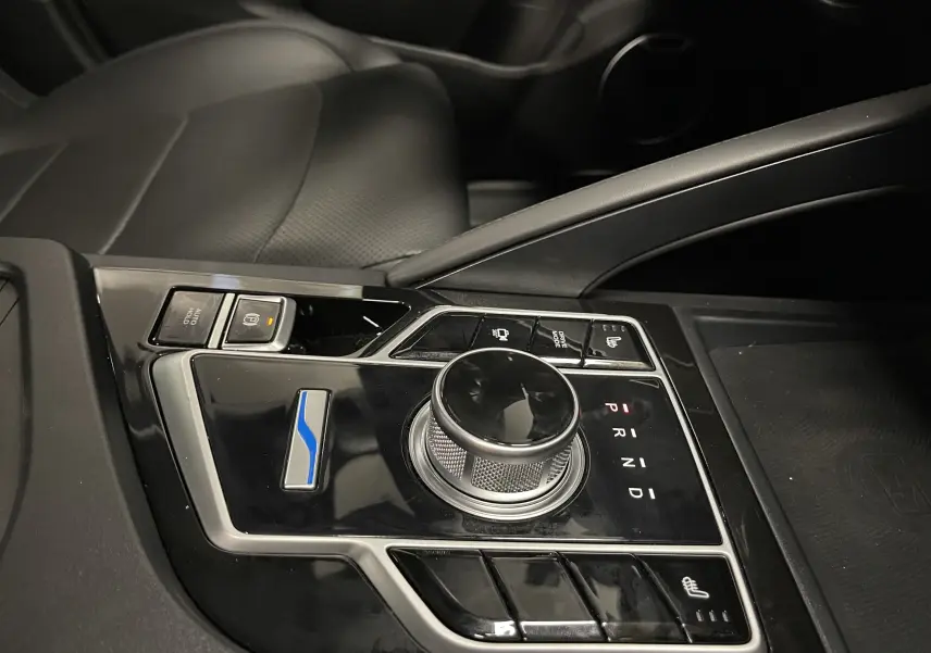 Gros plan sur la console centrale noire du SERES 3 Luxury blanc, mettant en valeur la molette de boîte auto et les commandes chauffantes.