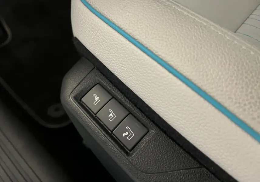 Détail des commandes de réglage électrique sous la sellerie ivoire soft touch avec surpiqûres bleues du Fiat 600 hybride 2024.