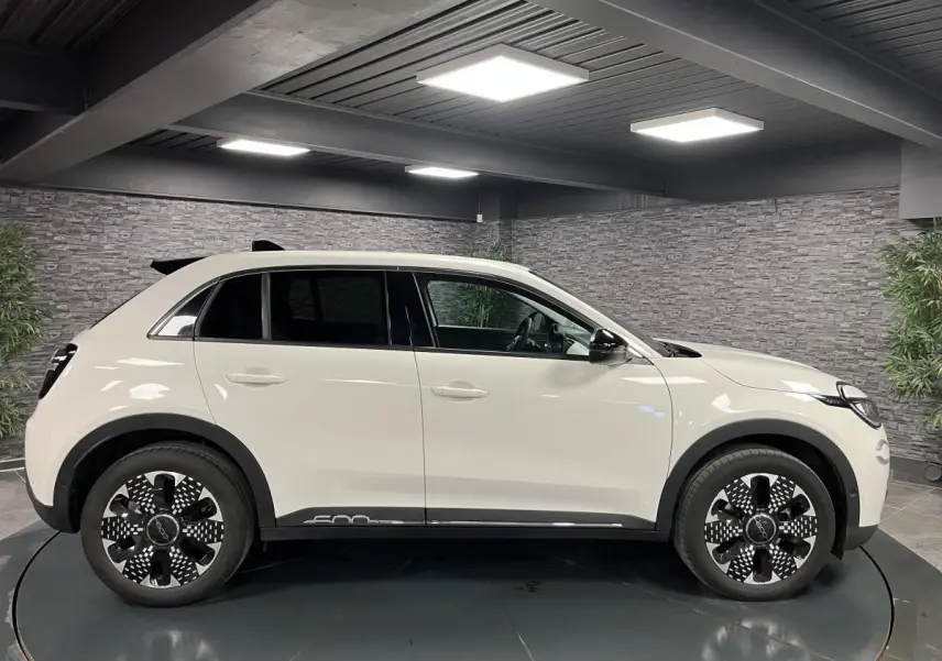 Vue de profil côté gauche d'un FIAT 600 blanc 2024 avec jantes alliage noires et logo 600 sur la bas de caisse.