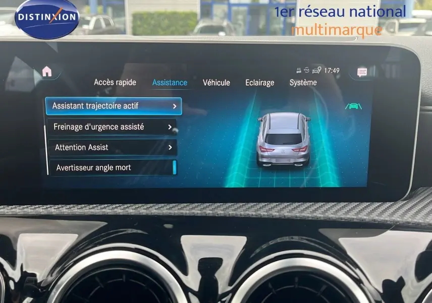 Écran central du tableau de bord d’une Mercedes CLA Shooting Brake 180 argent, affichant l’assistance à la conduite active.