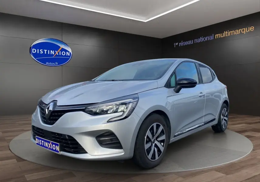 Renault Clio V TCE 90 Evolution gris Highland vue 3/4 avant droit avec vitres arrière surteintées et jantes spécifiques.