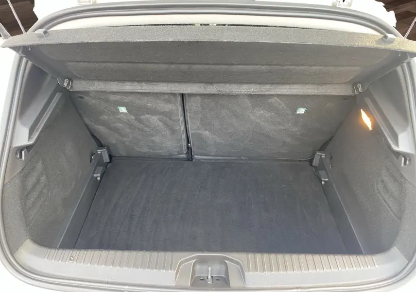 Coffre ouvert de la Renault Clio V TCE 90 Evolution gris Highland, montrant un compartimentage spacieux et tapis noir.