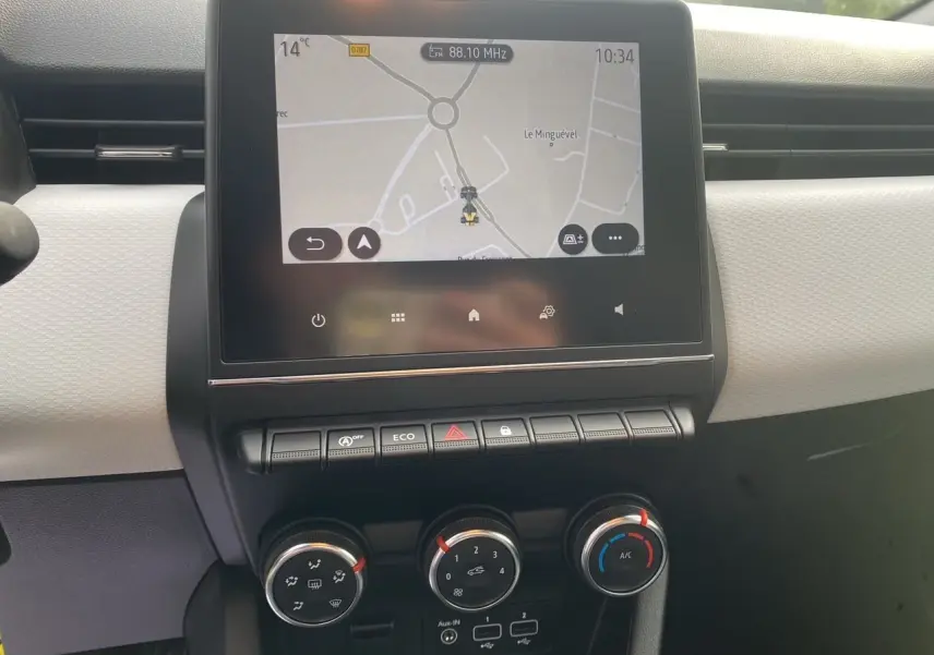 Vue rapprochée du tableau de bord beige et noir de la Renault Clio V avec écran tactile 7 pouces et commandes de climatisation.