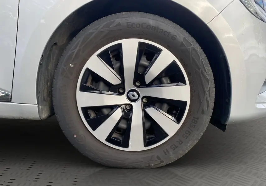 Gros plan sur la roue avant droite de la Renault Clio V gris Highland avec jante alliage bicolore et logo Renault central.