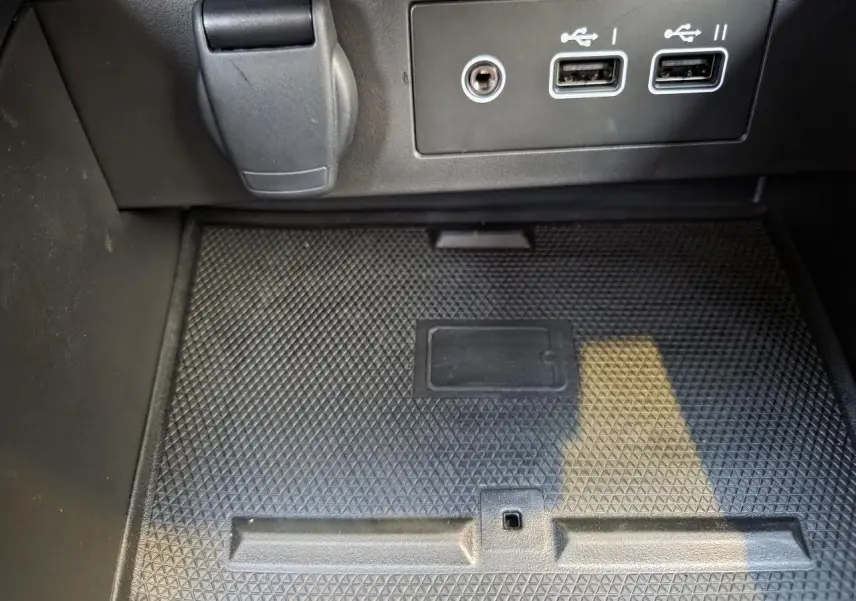 Gros plan sur la console centrale noire de la Renault Clio V hybride avec ports USB et prise 12V visibles.