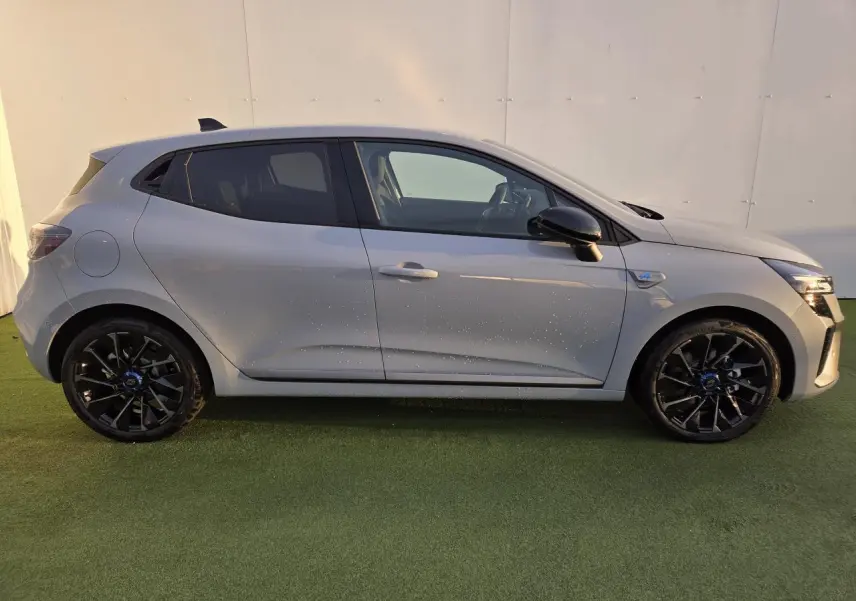 Profil droit d'une Renault Clio V hybride gris Rafale avec jantes alliage noires et rétroviseurs noirs brillants.