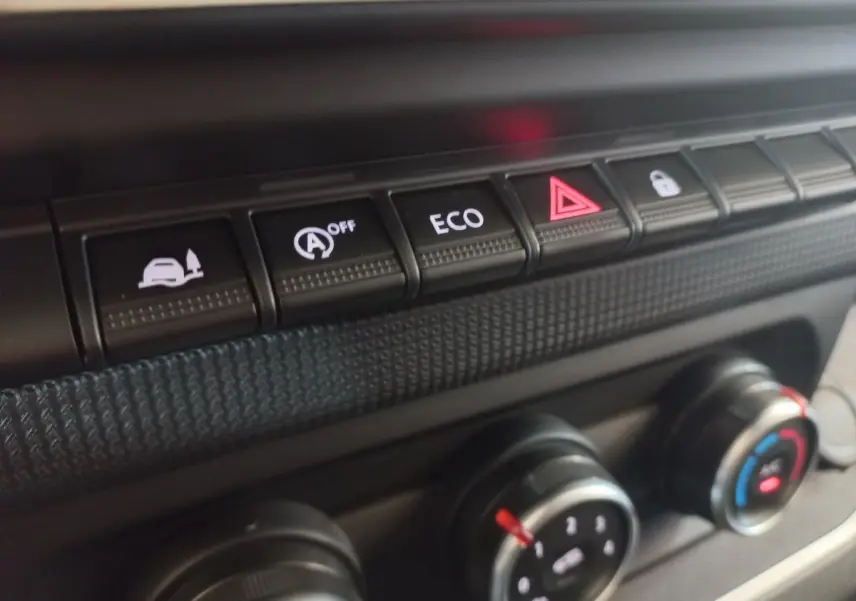 Gros plan sur les boutons de commande du tableau de bord du Renault Trafic Fourgon blanc, avec mode ECO et alerte.