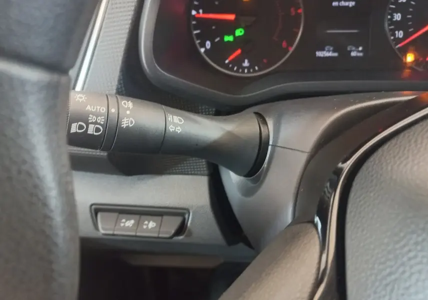 Gros plan sur la manette de commande des phares à gauche du volant dans le tableau de bord du Renault Trafic Fourgon blanc.