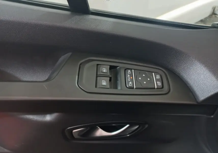 Gros plan sur la commande des vitres et rétroviseurs côté conducteur du Renault Trafic Fourgon blanc, intérieur noir.