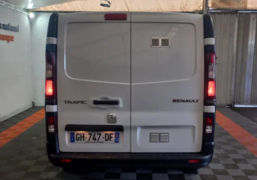 Vue arrière d’un Renault Trafic Fourgon blanc 2022 avec feux arrière allumés et plaques d’immatriculation françaises.