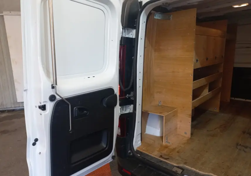 Vue arrière droite du Renault Trafic Fourgon blanc 2022 avec porte ouverte montrant l'aménagement bois intérieur.