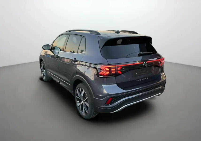 Volkswagen T-Cross TSI 116 DSG7 R-Line gris cendré vu en 3/4 arrière droit avec feux arrière LED allumés.