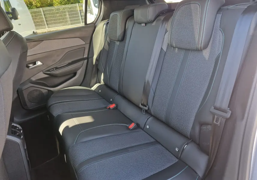 Vue latérale droite de la banquette arrière en tissu et cuir noir avec surpiqûres bleues dans une Peugeot 308 gris Artense 2025.