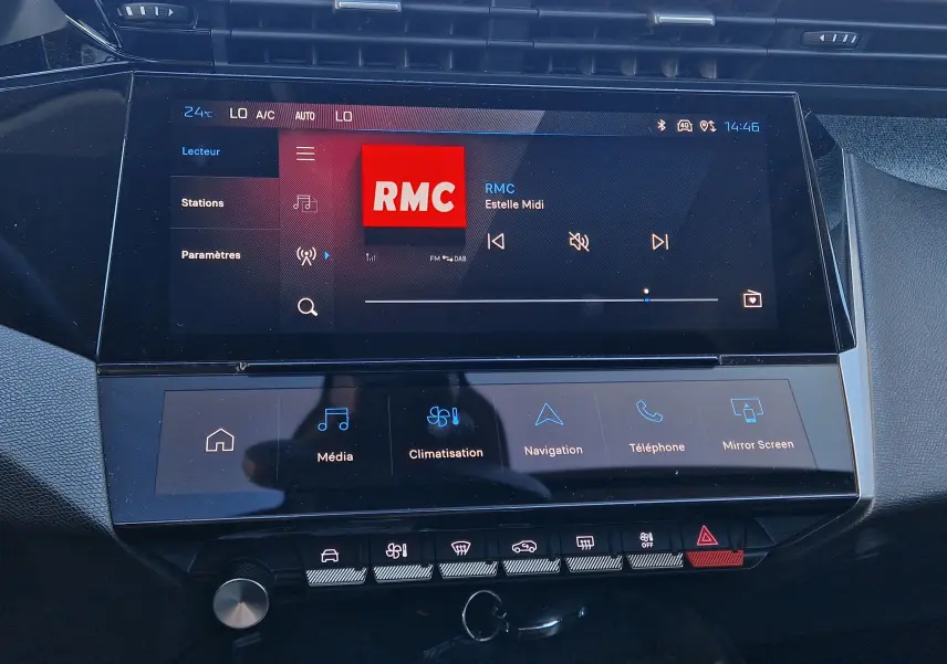 Vue rapprochée de l'écran tactile central du tableau de bord de la Peugeot 308 1.2 Hybrid 145 Allure, affichant la radio RMC.