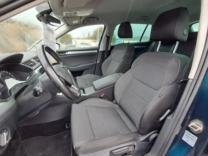 Intérieur avant du Skoda Superb Combi bleu métal 2018, vue côté conducteur avec sièges tissu gris et tableau de bord visible.