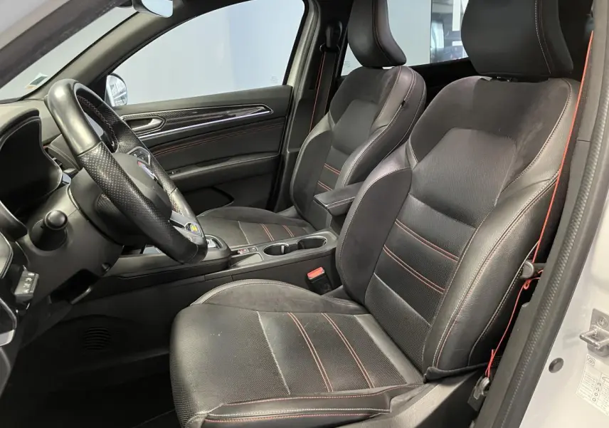 Intérieur côté conducteur du Renault Arkana blanc 2022, sièges R.S. Line cuir-suédine noirs avec surpiqûres rouges.