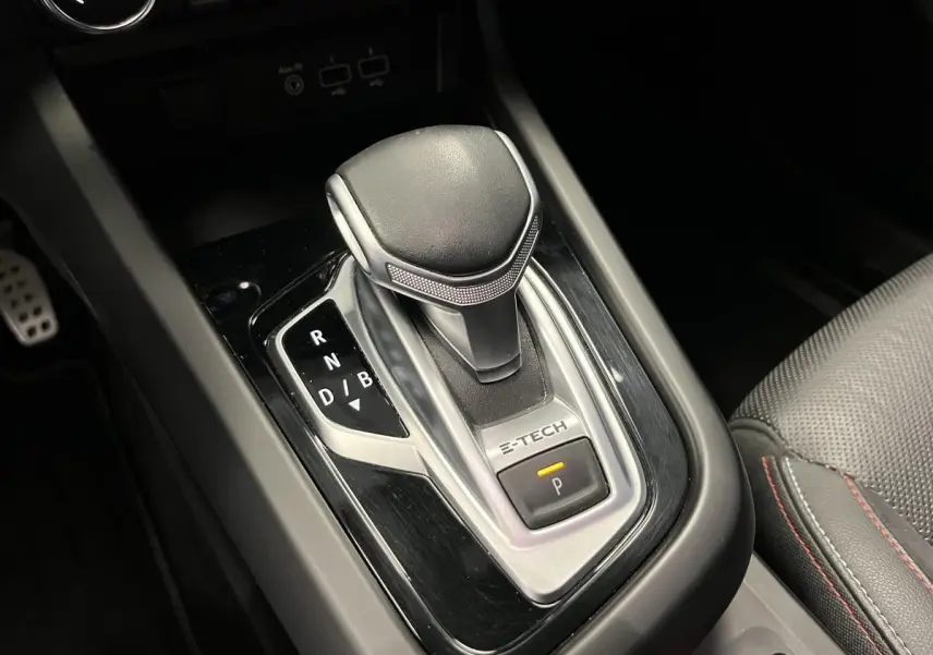 Levier de vitesse e-shifter E-Tech en gros plan dans l'habitacle du Renault Arkana blanc, surpiqûres rouges visibles sur siège cuir.