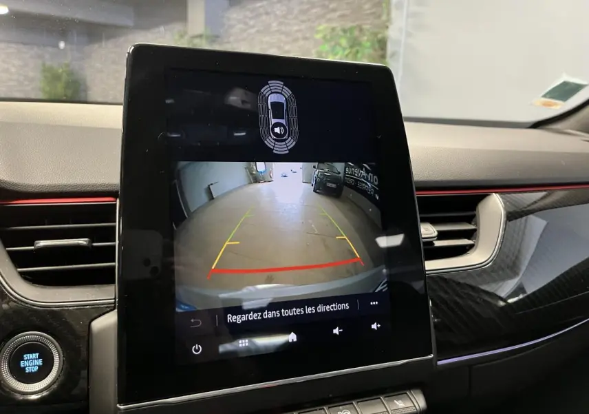 Écran tactile central affichant la caméra de recul dans l’habitacle du Renault Arkana blanc, avec détails carbone et liseré rouge.