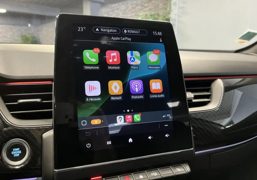 Écran tactile central affichant Apple CarPlay dans l'habitacle du Renault Arkana blanc avec finition R.S. Line.