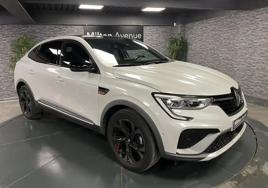 Renault Arkana 1.6 E-Tech Hybride blanc perle en 3/4 avant avec toit et rétroviseurs noirs brillants et jantes noires.