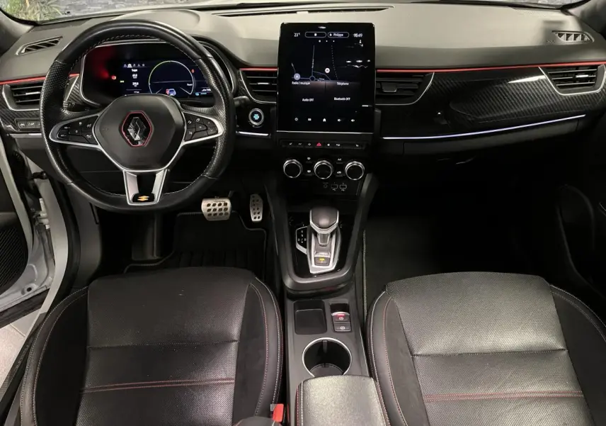 Intérieur avant du Renault Arkana 1.6 E-Tech Hybride 2022 avec volant sport, écran tactile vertical et surpiqûres rouges R.S. Line.